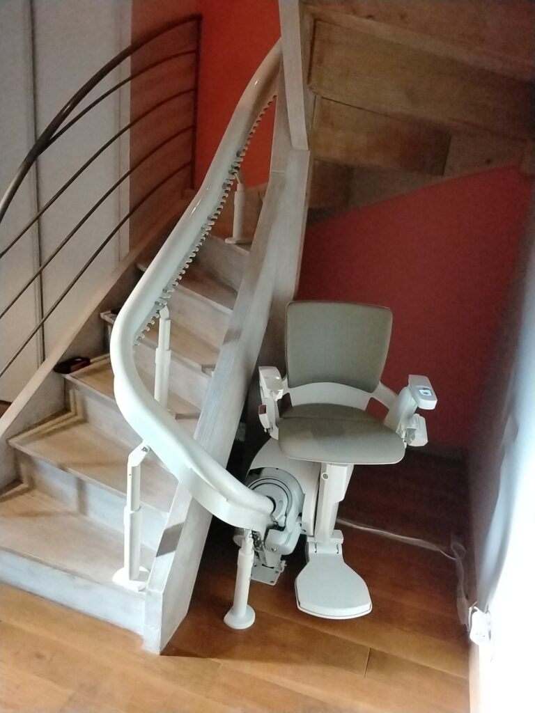 Siège du monte-escalier courbe Otolift Modul’Air Smart en bas d'un escalier bois à Limoges (87)